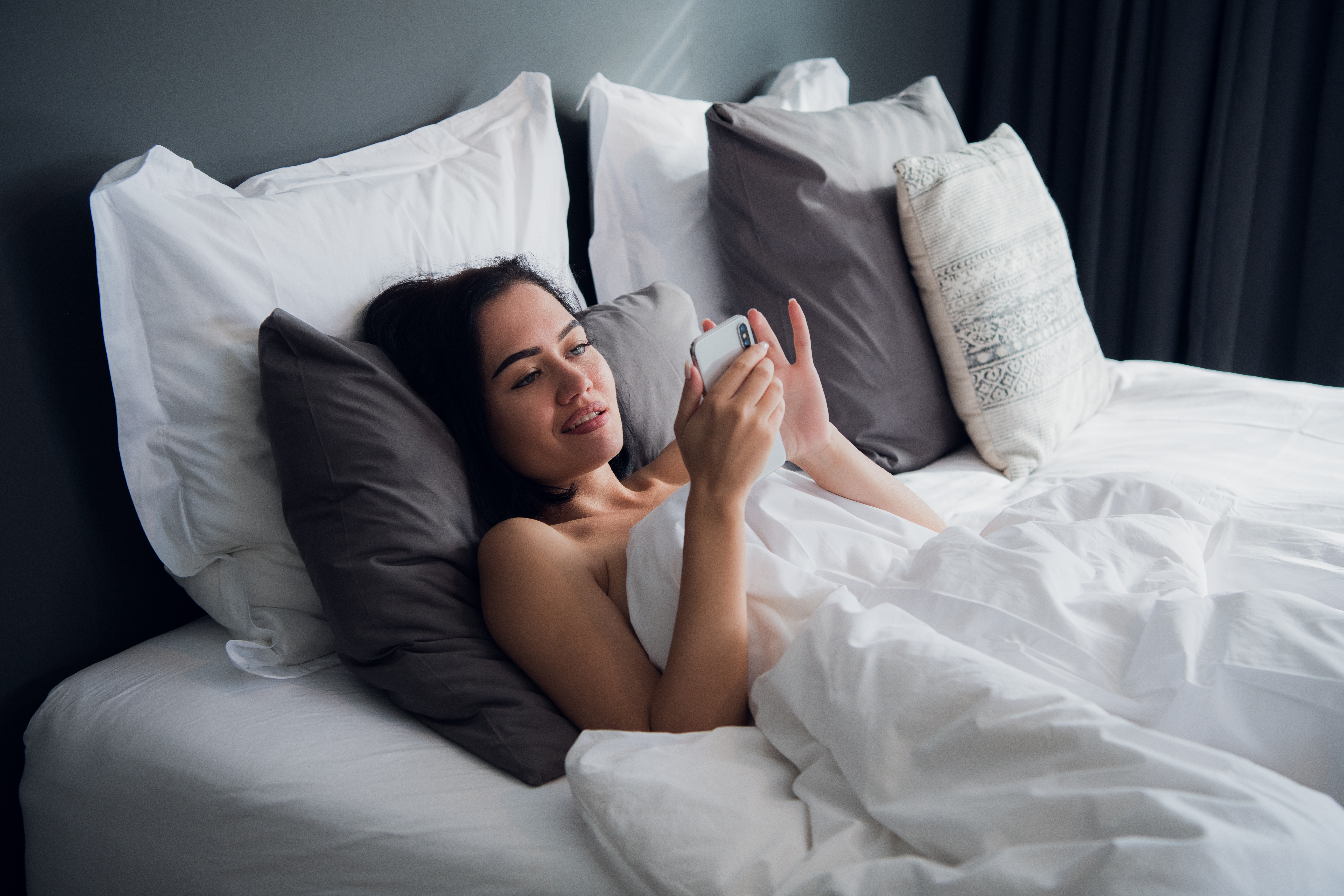 Девушка лежа на кровати снимает на видео камеру домашнюю мастурбацию
