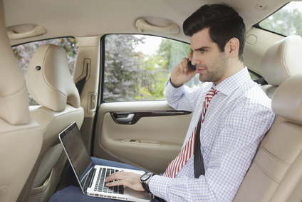 Businessman with laptop on the knee in his car
