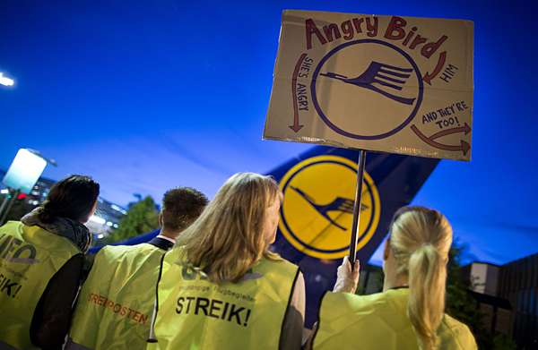 Cabin staff of German airline Lufthansa hold up a poster with their company's logo, a crane, as they strike on August 31, 2012 at the airport in Frankfurt/M., western Germany. Lufthansa has been forced to cancel "a large part" of its 360 scheduled flights in and out of Frankfurt on Friday morning owing to walkouts by cabin staff, the company said. Primarily affected were domestic and European flights, but a small number of long-haul services was also being hit by knock-on effects. Cabin staff are staging the strike in their fight for higher pay. AFP PHOTO / FRANK RUMPENHORST GERMANY OUT
