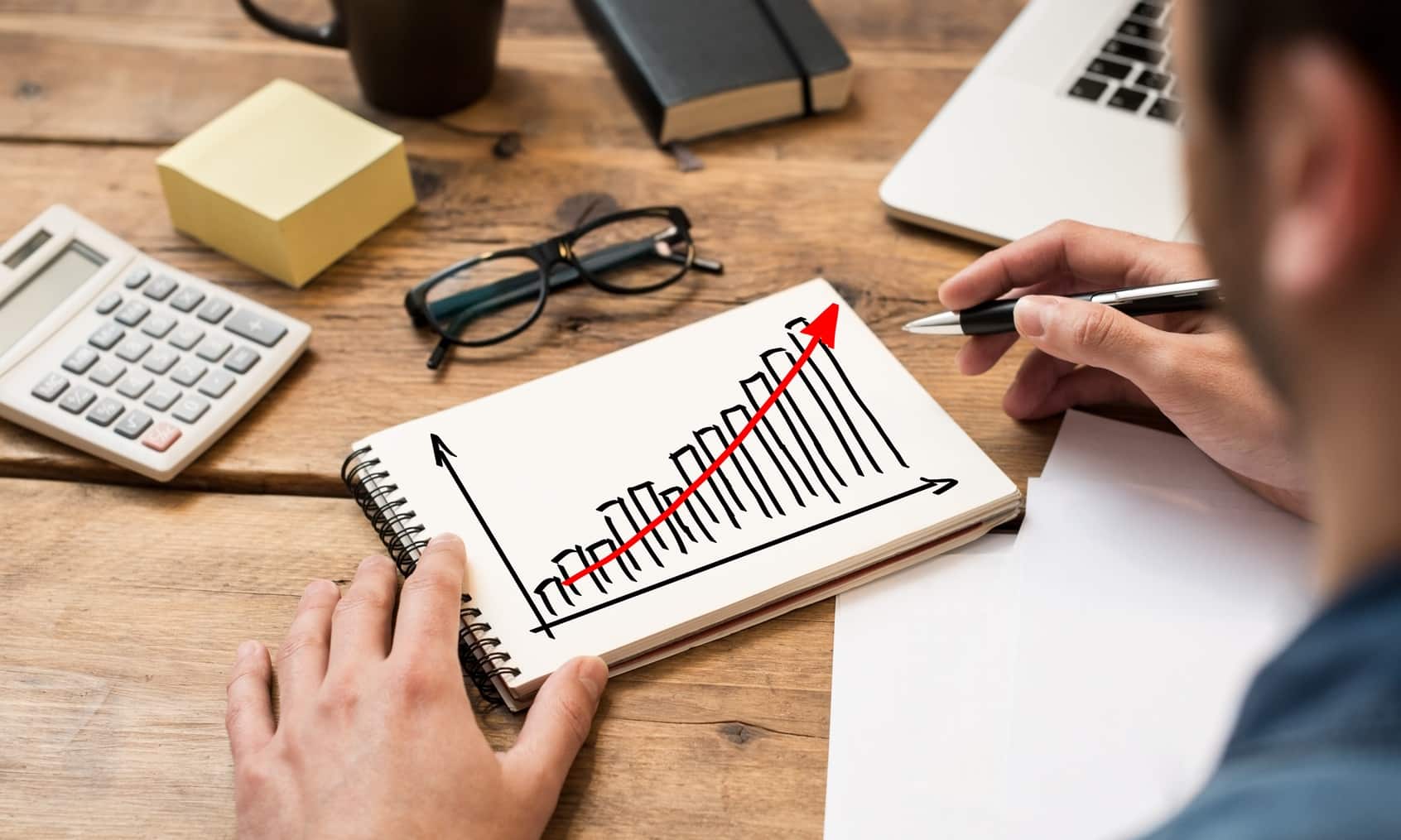 Businessman drawing a growing chart on a paper notebook