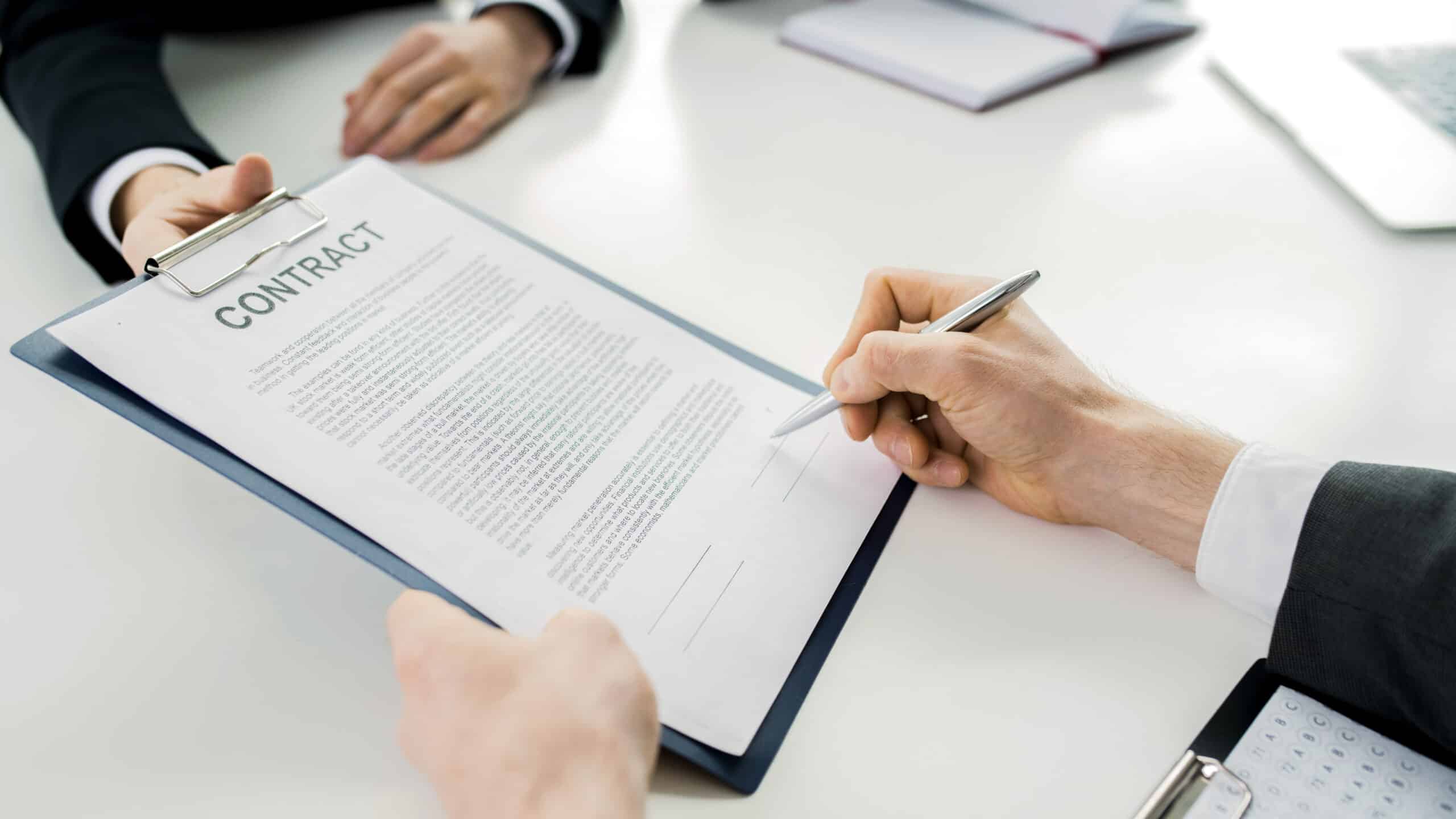 Close up of unrecognizable businessman signing contract during meeting with partners at table in conference room, copy space