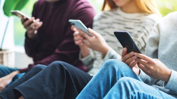 Group of young people using and looking at mobile phone while si